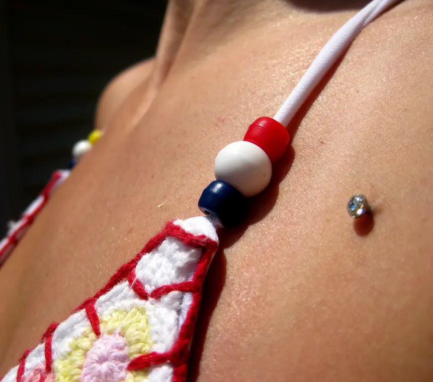 A single gem dermal anchor sitting flush against the skin of the upper chest, with no second exit point