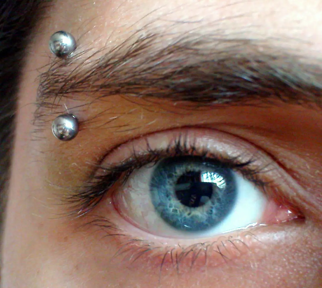 An eyebrow piercing with two rounded ends sitting above and below the outer brow