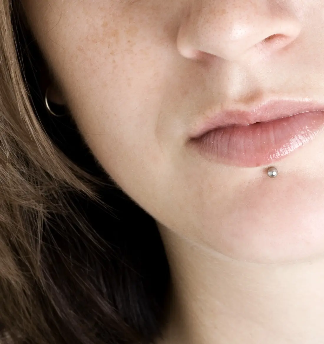 A silver labret stud just below the centre of the lower lip