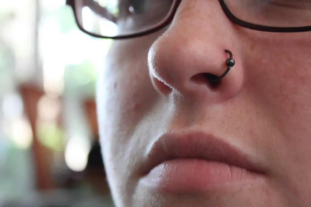 Close-up of a thin black hoop in a healed nostril piercing