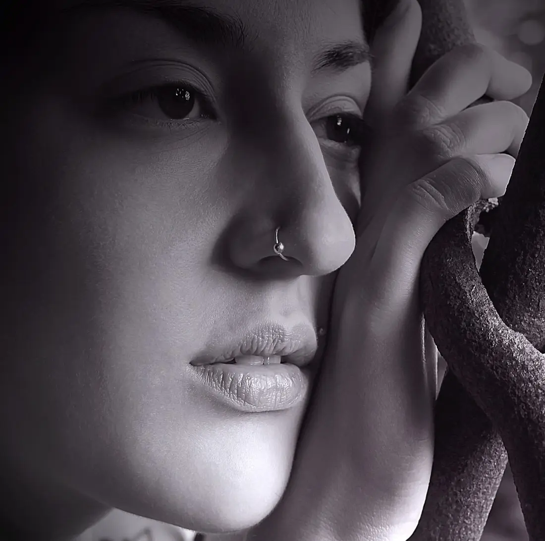 Black-and-white close-up of a small stud in the crease of the nostril
