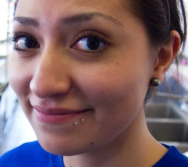 Two small silver studs set close together below one side of the lower lip