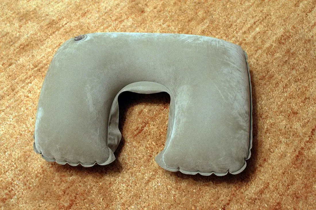 A grey inflatable U-shaped travel pillow, the kind used to keep pressure off a fresh ear piercing while sleeping